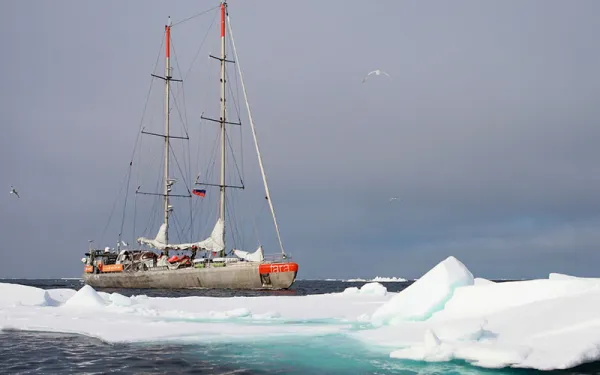 Boat in the ocean next to iceberg